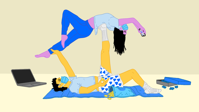 Two people perform a balancing act on a blue mat, surrounded by snacks and a laptop. One holds a phone.