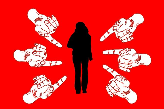 A silhouetted woman stands surrounded by multiple pointing hands on a red background.